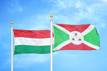 Hungary and Burundi  two flags on flagpoles and blue cloudy sky