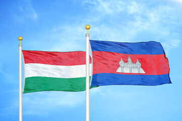 Hungary and Cambodia  two flags on flagpoles and blue cloudy sky