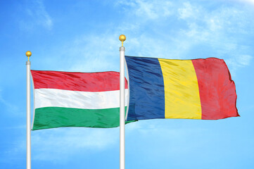 Hungary and Chad  two flags on flagpoles and blue cloudy sky