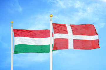 Hungary and Denmark two flags on flagpoles and blue cloudy sky