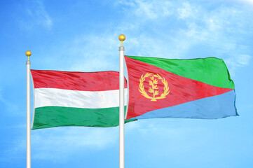Hungary and Eritrea two flags on flagpoles and blue cloudy sky