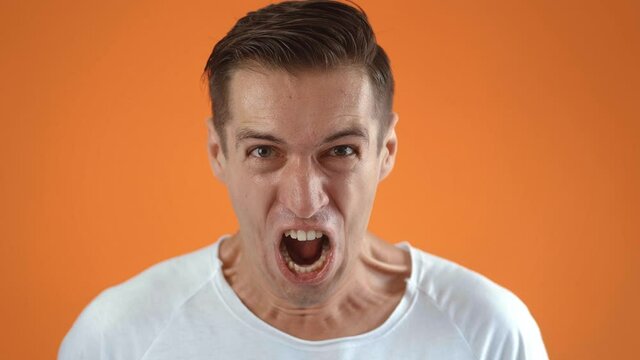 Portrait of a screaming man on an orange background. Sports fan rejoices for winning sports team bet match