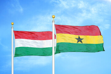 Hungary and Ghana two flags on flagpoles and blue cloudy sky