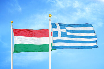 Hungary and Greece two flags on flagpoles and blue cloudy sky