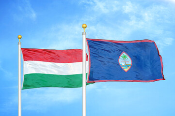 Hungary and Guam two flags on flagpoles and blue cloudy sky