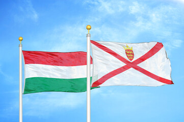 Hungary and Jersey two flags on flagpoles and blue cloudy sky