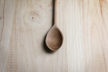 Wooden kitchen spoon on light wooden background