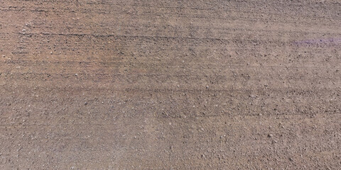 view from above on surface of gravel road with car tire tracks