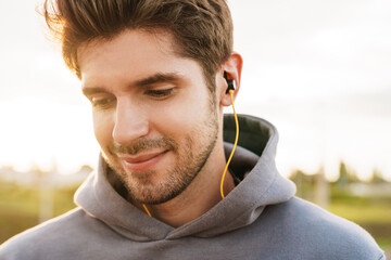 Obraz premium Image closeup of athletic bristle sportsman using earphones and smiling