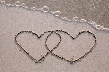 Two hearts drawn on the sand of a sea beach.