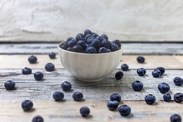 Blueberries in a white cup on a white wooden background. Concept for healthy eating. Antioxidant organic superfood.