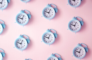 Blue alarm clocks on a pastel pink background.