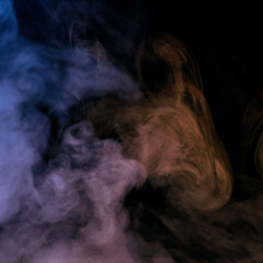 Conceptual image of multi-colored smoke isolated on dark black background and wooden table.