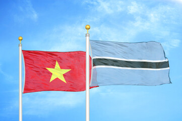 Vietnam and Botswana  two flags on flagpoles and blue sky