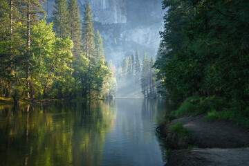 sunbeams on a foggy morning over merced river in yosemite national park