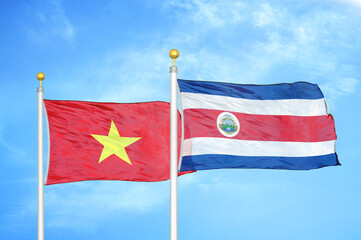 Vietnam and Costa Rica two flags on flagpoles and blue sky