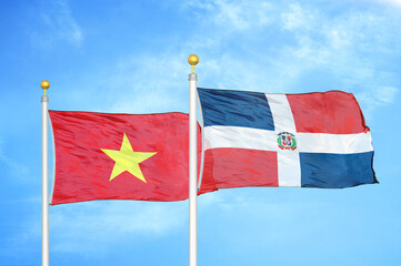 Vietnam and Dominican Republic two flags on flagpoles and blue sky
