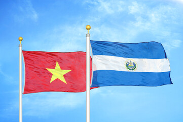 Vietnam and El Salvador two flags on flagpoles and blue sky