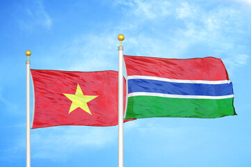 Vietnam and Gambia two flags on flagpoles and blue sky