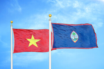 Vietnam and Guam two flags on flagpoles and blue sky