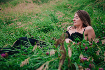 Beautiful girl in black bra and long skirt lies in the grass