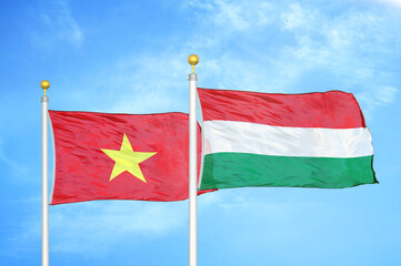 Vietnam and Hungary two flags on flagpoles and blue sky