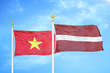Vietnam and Latvia two flags on flagpoles and blue sky