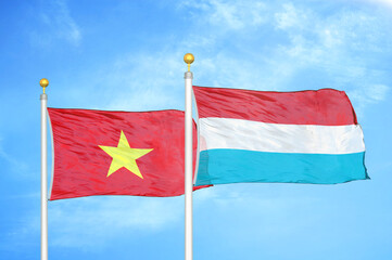 Vietnam and Luxembourg two flags on flagpoles and blue sky