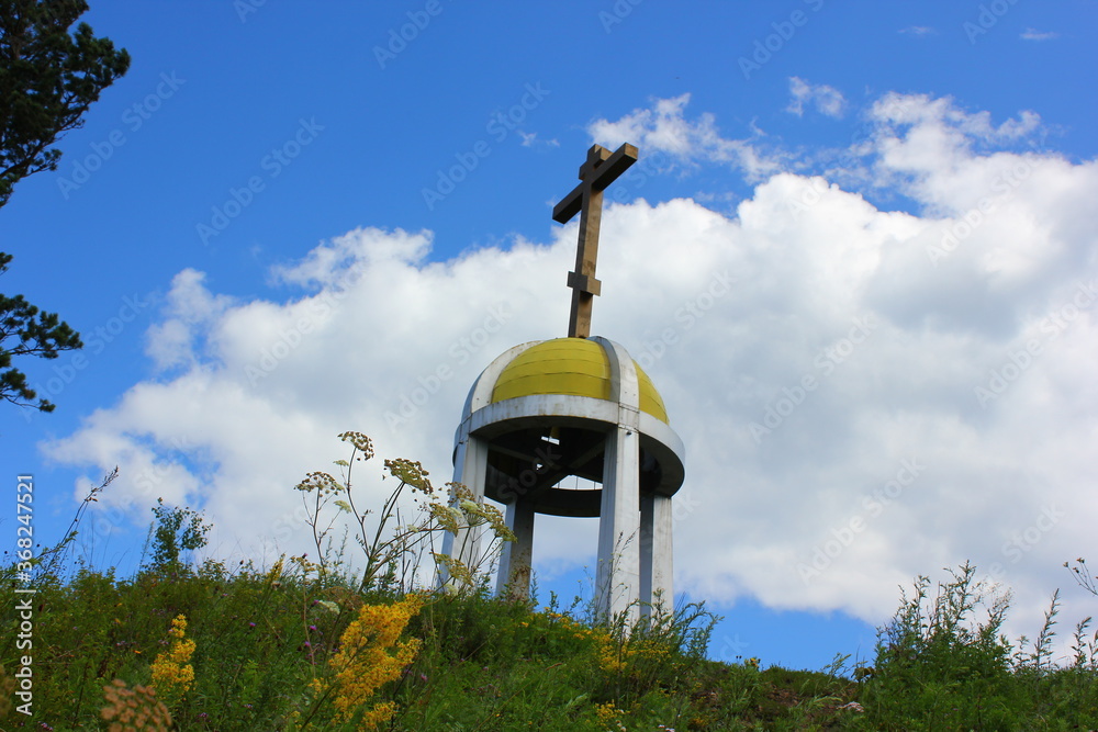 Wall mural the dome of the chapel with a cross on the background of the sky with clouds