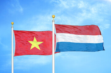 Vietnam and Netherlands two flags on flagpoles and blue sky