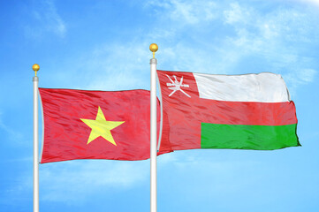 Vietnam and Oman two flags on flagpoles and blue sky