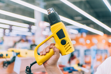 The man is holding an electric hairdryer. Concept man selects a product in a hardware store.