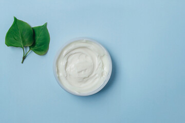 Organic cosmetics:  face cream, on light blue background, top view. Beauty routine concept.