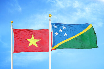 Vietnam and Solomon Islands two flags on flagpoles and blue sky
