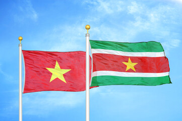 Vietnam and Suriname two flags on flagpoles and blue sky