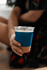 Woman holding iced coffee.