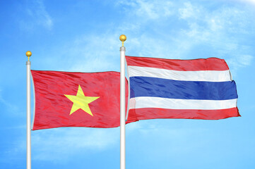 Vietnam and Thailand two flags on flagpoles and blue sky