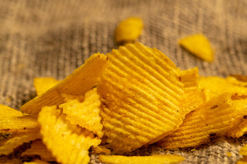 Fluted potato chips on a background of homespun fabric with a rough texture. Close up.