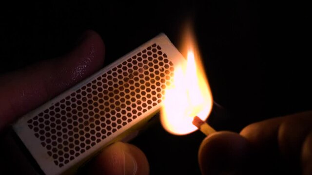 Wet fingers striking a match, slow motion