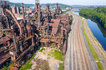 Aerial of abandoned steel factory in Pennsylvania with train tracks and a river alongside.