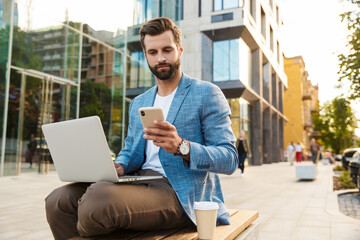 Confident male manager with laptop and smart phone