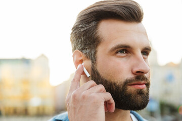 Obraz premium Confident young man wearing wireless earphones
