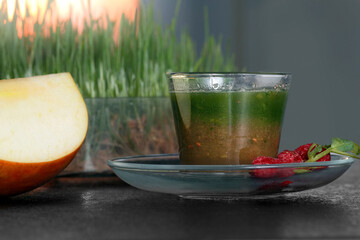 drink from the juice of wheat sprouts, on the background of diaper sprouts, with elements of apple and raspberry