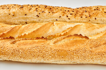 Close up of crusty baguettes with sesame and flax seeds. Fresh crispy bead. Unhealthy eating concept.