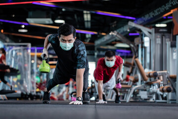 young mam and friend working out wearing surgical mask & latex rubber gloves, COVID-19 pandemic...