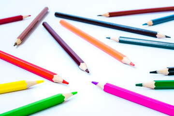 Colored pencils on a white background. Pencils scattered randomly. Stationery. Goods for school and kindergarten.