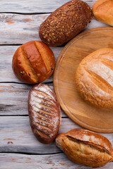 Top view of various bakery products on wooden background. Freshly baked artisan bread on wood boards.
