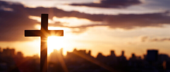 Silhouette cross against the sky At Sunset. Dramatic city background. Crucifixion Of Jesus Christ. Religion concept.
