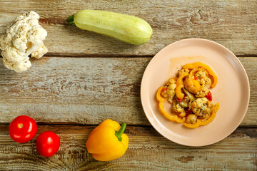 Vegetable stew on a beige plate on a wooden table Nearby vegetables.