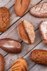 Top view of assorted artisan bread loaves. Freshly baked rustic bread on wooden background.